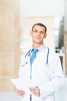 Portrait of a doctor holding papers in hand, office space