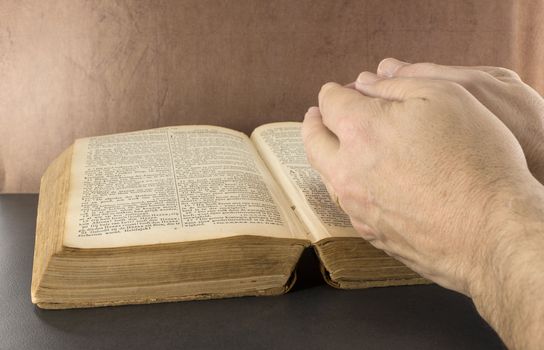 praying hand with old bible book with brown background