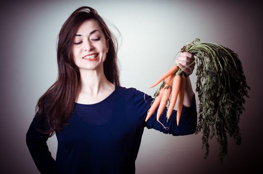 beautiful woman with carrots on gray background