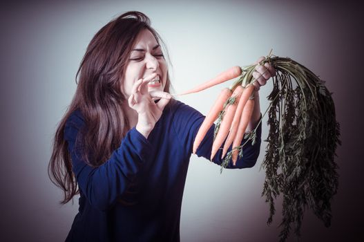 beautiful woman with carrots on gray background