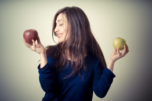 beautiful woman choosing red or yellow apples on gray background