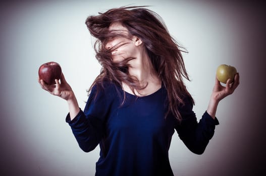 beautiful woman choosing red or yellow apples on gray background