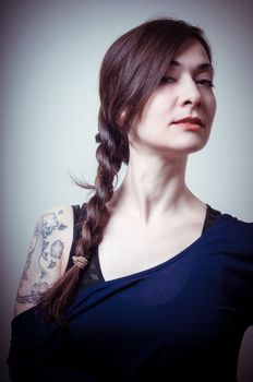 portrait of beautiful girl with long hair and blue sweater on gray background