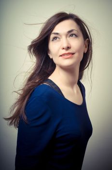 portrait of beautiful girl with long hair and blue sweater on gray background