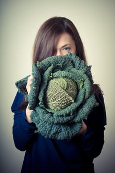 beautiful woman with savoy cabbage on gray background