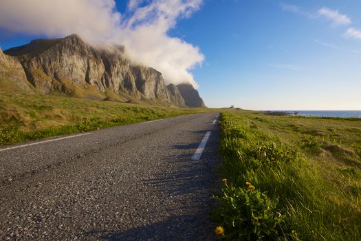 Scenic coastal road under the cliffs of island Vaeroy on Lofoten, Norway