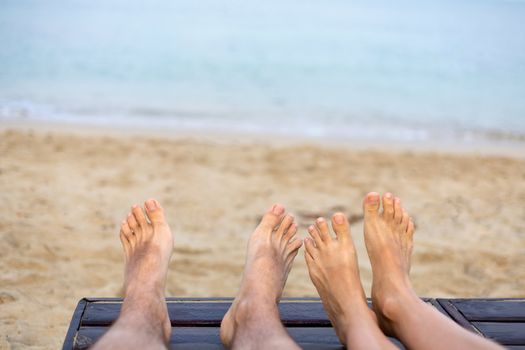 wo pairs of legs of people in love on the azure sea at sunset