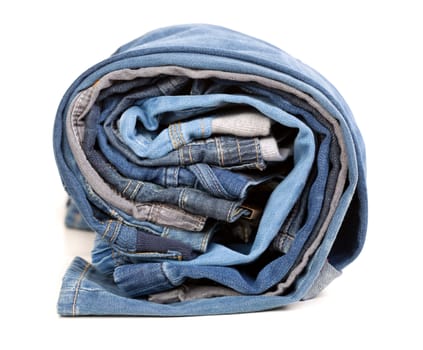 Different jeans rolled up on a white background