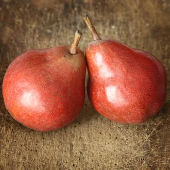 two red pears on wooden table close up