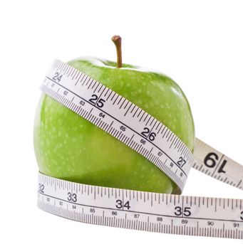 A green shiny apple, wrapped with a white metric and imperial measuring tape to signify dieting and weight loss.  Isolated on white background with slight shadows retained.