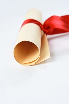 A rolled scroll of parchment coloured paper, tied with red ribbon to signify a diploma or award.