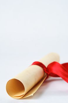 A rolled up parchment scroll, tied with a red ribbon to suggest graduation diploma or award.