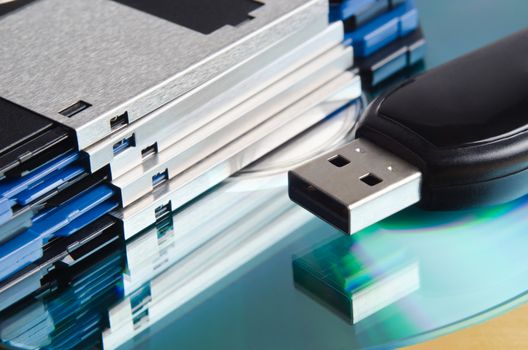 Close up (macro) of a selection of old and new storage media.  Three and a quarter inch floppy disks, CD-ROM and USB memory stick.