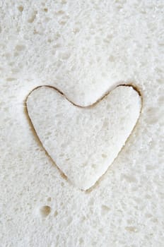 Close up (macro) of white bread with a heart shape cut into it.