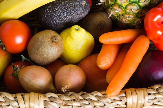 Overhead shot of a basket crammed with raw, fresh, colourful fruit and vegetables.  Landscape orientation.