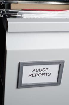An open filing drawer containing hanging files and documents, labeled 'Abuse Reports'.  Portrait orientation.