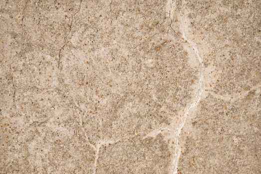 Background texture.  Light beige coloured old stone wall with cracks and small pieces of grit on surface.