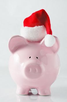 A piggy bank wearing a santa hat to signify saving money to plan ahead for the cost of Christmas.