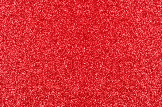 A Christmas texture background of red glitter, evenly spread from edge to edge of frame.