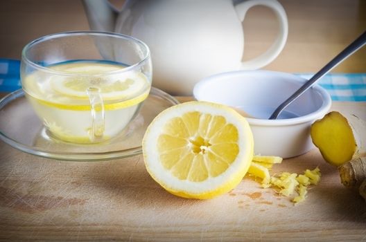 Kitchen preparation scene containing ingredients for a honey, lemon and ginger drink - a herbal home remedy for colds.  