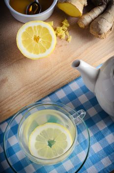 Vertical kitchen preparation scene containing ingredients for a honey, lemon and ginger drink - a herbal home remedy for the cold and flu season.