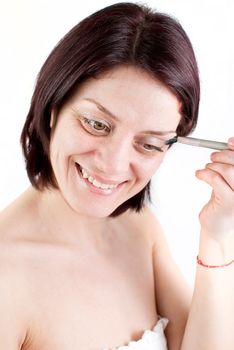 Closeup portrait of a happy young woman applying make up on her face