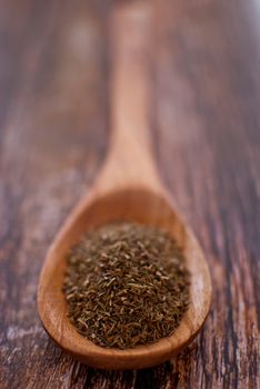 thyme spice in wooden spoon over wood background - selective focus