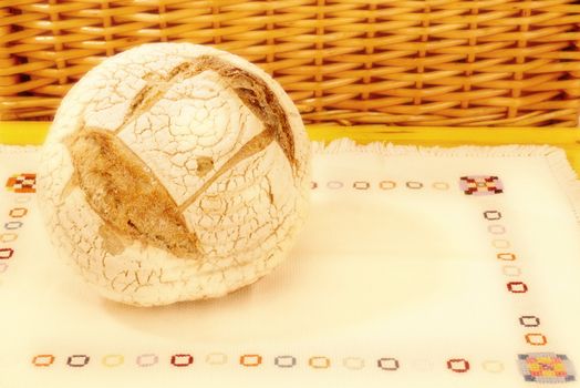 Ecological round bread made ??with a wooden table with embroidered tablecloth