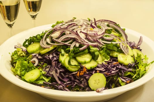 Mixed salad dish with white wine glasses