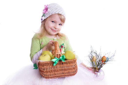 Smiling girl with basket full of apples and some flowers on white