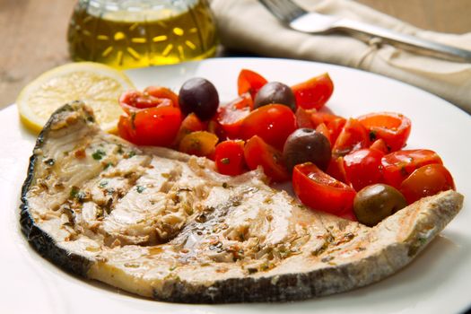 swordfish with tomatoes and lemon on wood