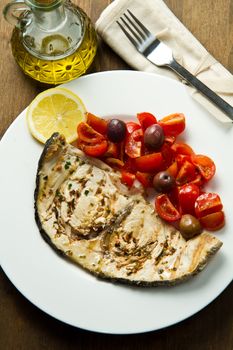 swordfish with tomatoes and lemon on wood