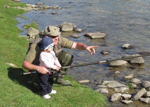 father and daughter fishing on river on summer day 