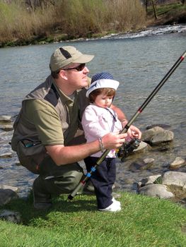 father and daughter fishing on river on summer day 