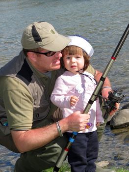 father and daughter fishing on river on summer day 