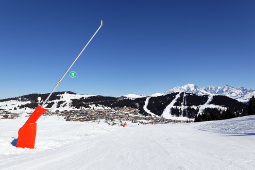 snowmaker on ski track in alpine mountain