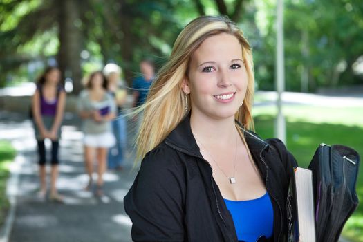 Portrait of young girl smiling with her classmates walking in the background