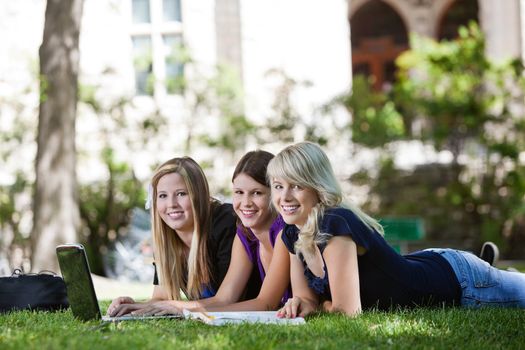 Three female university students outdoors with laptop