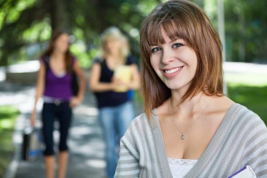Portrait of smiling young college girl with her friends in background