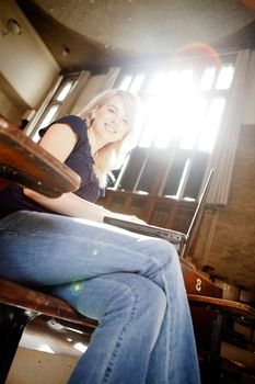 Happy portrait of a young blond college girl in lecture theater with laptop