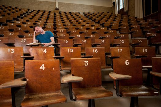 Male university student asleep in a large lecture hall