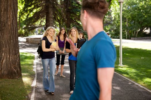 Male student waving to a group of female students