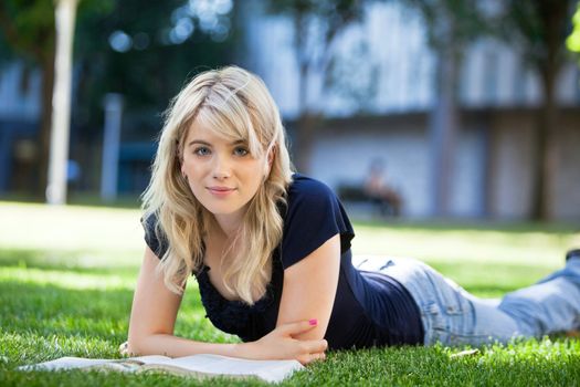 Relaxed female student lying on grass at college campus