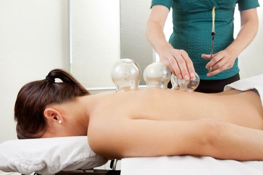 Acupuncture therapist placing a cup on the back of a female patient