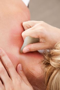 Female receiving gua sha treatment to neck and shoulders