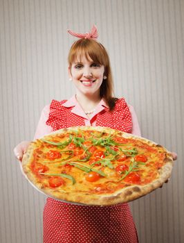 Young housewife holding a vegetarian pizza for lunch