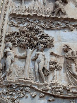 Orvieto - Duomo facade. The first pillar: scenes from Genesis. In the company of angels, God forbids Adam and Eve eat the fruit from the tree