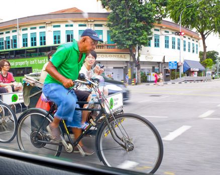 Man pedalling a rickshaw carrying tourists, Singapore.
