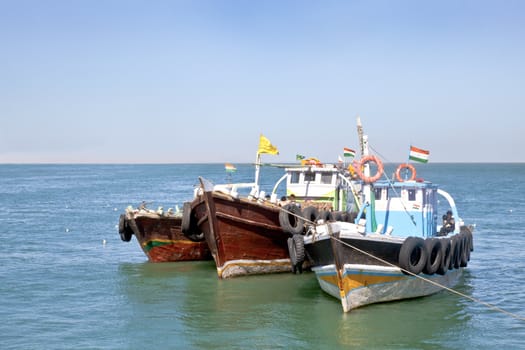Horizontal seascape of Indian passenger ferries moored under a blue sky at Bet Dwarka, Gujarat, India