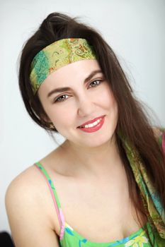 Beautiful young woman with long brunette hair in green summer outfit wearing a sleeveless dress and headband